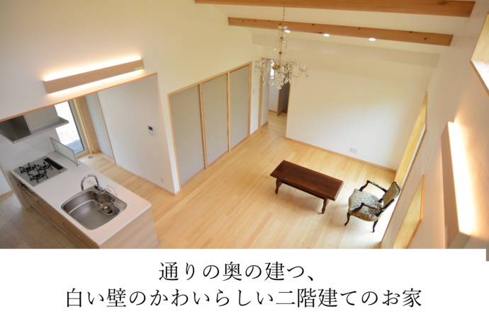 通りの奥の建つ、 白い壁のかわいらしい二階建てのお家